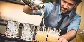 Barista schenkt aus Cocktail-Shaker in Gläser ein