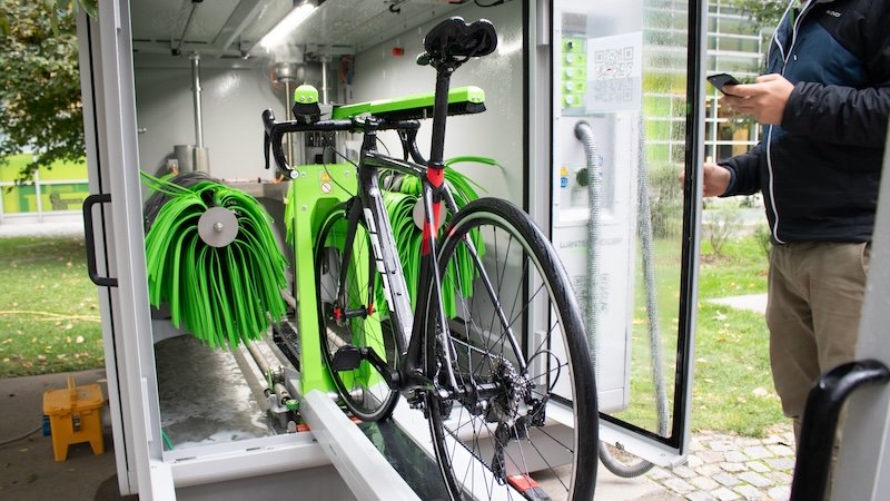 Grünes Fahrrad, das in der vollautomatischen Fahrradwaschanlage steht. 