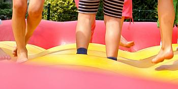 Kinderbeine von den Knien abwärts auf einer Hüpfburg fotografiert