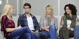 Drei Frauen und ein Mann sitzen in einem Halbkreis zusammen