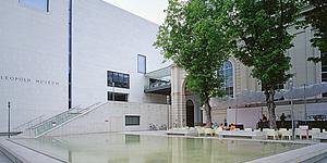 Außenansicht Leopold Museum Wien mit kleinem Teich davor und grünem Bäumen im Bild
