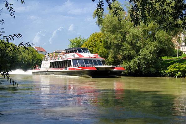 Schiff auf der Donau vor grünen Bäumen und Sträuchern