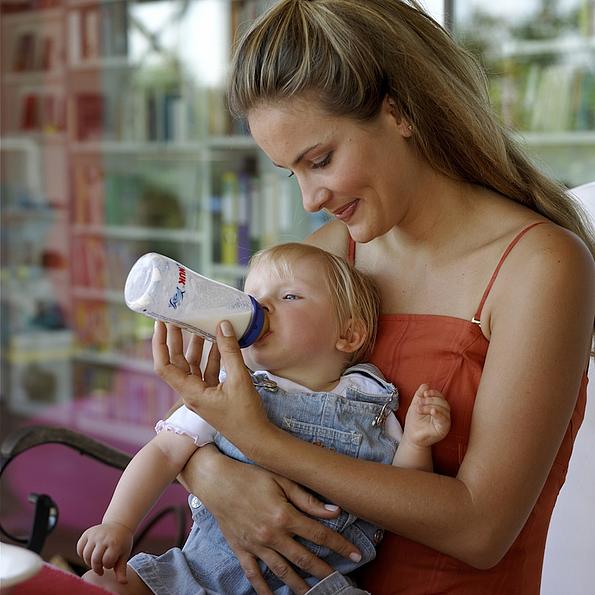 Frau füttert Baby mit Milchfläschchen