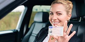 Frau hält lachend Scheckkarten-Führerschein in die Kamera