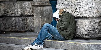 frierender Obdachloser sitzt auf Treppe