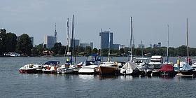 Das Bild zeigt Segelboote auf der Alten Donau, im Hintergrund ist das Vienna International Centre zu sehen.
