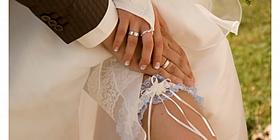 Bräutigam streichelt das Bein der Braut mit Strumpfband