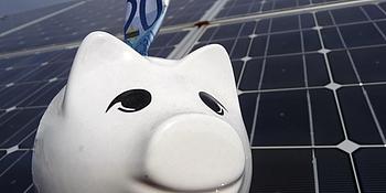 Sparschwein vor Solarmodul einer PV-Anlage