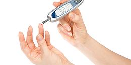Diabetiker misst Blutzuckerwerte mittels Nadel und Teststreifen über Blut das aus dem Finger tropft.