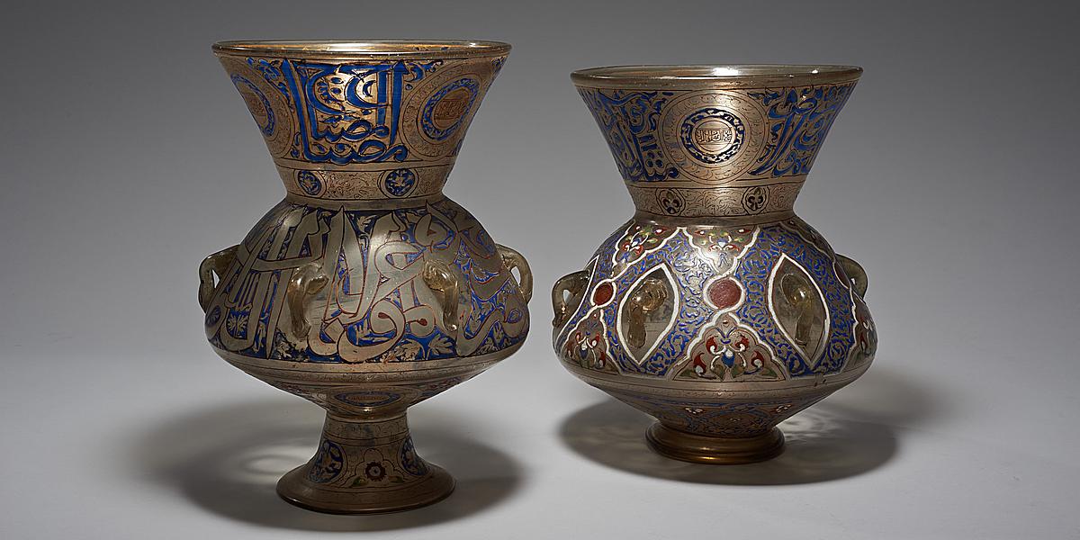 Zwei Gefäße mit Ähnlichkeit zu Vasen als Ausstellungsobjekte im Weltmuseum Wien. Diese beiden Moscheeampeln sind bunt verziert mit Emaildekor und haben eine Vergoldung.