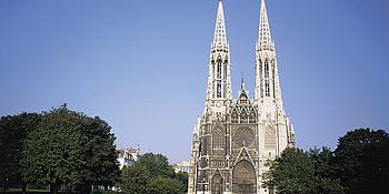 Frontalansicht der Votivkirche in Wien vom Sigmund Freud Park aus gesehen.