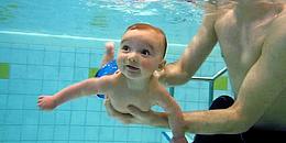 Baby mit Papa im Schwimmbad am Tauchen