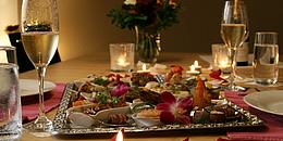 Romantisches Abendessen mit Kerzen, Blumen und Sektgläsern, sowie einer Platte für 2