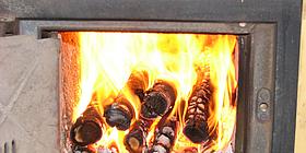 Ofene Kachelofenklappe mit brennenden Holzstücken