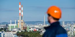 Blick auf das Kraftwerk Simmering Wien mit im Vordergrund stehender Arbeiter mit orangem Helm