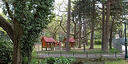 Ein Park mit 2 kleinen Häuschen als Kinderspielplatz
