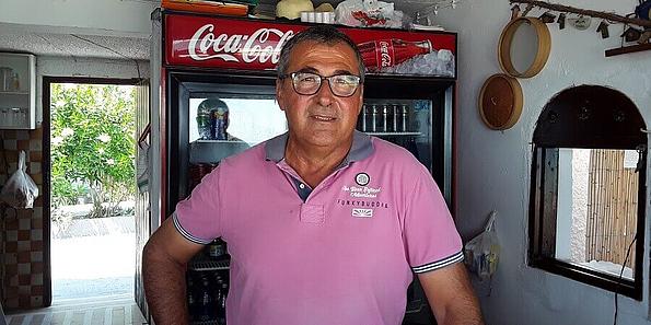 Mann in rosa Tshirt vor Cola-Getränkkühlschrank