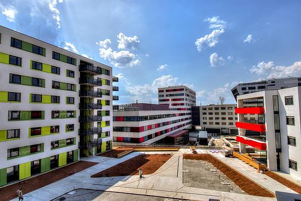 Studierendenheim Base 22 von Außen. 5 Wohngebäude mit weiß-grüner, bzw. weiß-roter Fassade.