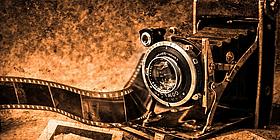 Alte Kamera mit Filmstreifen in brauntönen gehalten.