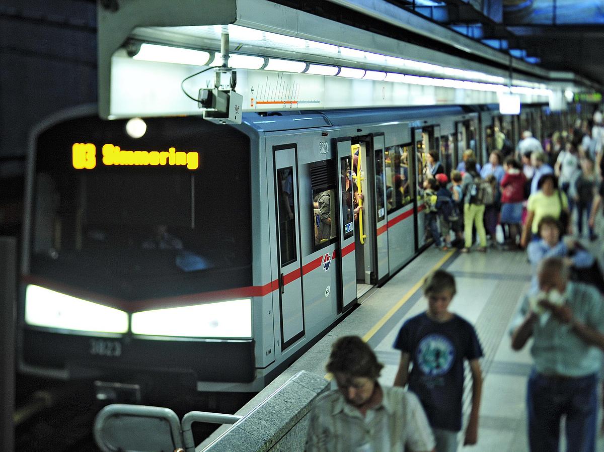 Zug der U-Bahn-Linie U3 steht in Station Volkstheater. Viele Fahrgäste steigen ein und aus.