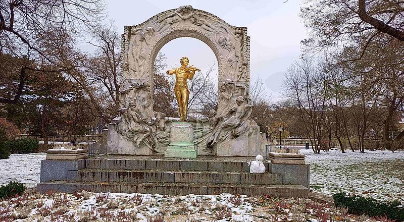 Eine goldene Statue des Komponisten Johann Strauß steht auf einer schneebedeckten Wiese