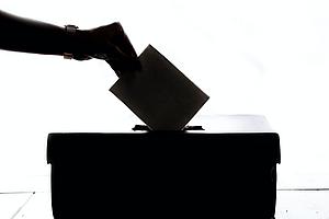 Hand gibt Stimme in eine Wahlurne