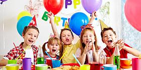 Kinder bei einer Geburtstagsfeier mit buntem Geschirr und Luftballons