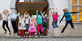 Kinder machen Luftsprünge vor dem Mozarthaus Vienna