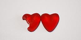 Zwei rote Herzen, davon ein angebissenes, vor weißem Hintergrund