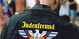 Pressebild des Jüdischen Museums zeigt glatzköpfigen Mann in Lederjacke von hinten, Jacke mit Aufschrift "Judenfreund"