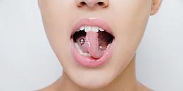 Frau mit Zungenpiercing streckt Zunge heraus