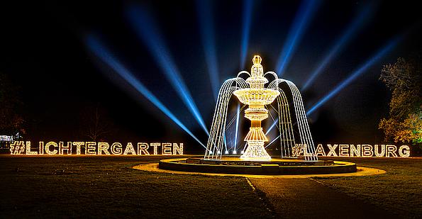 Beleuchteter Schriftzug "#Lichtergarten" "#Laxenburg" hinter beleuchtetem Brunnen