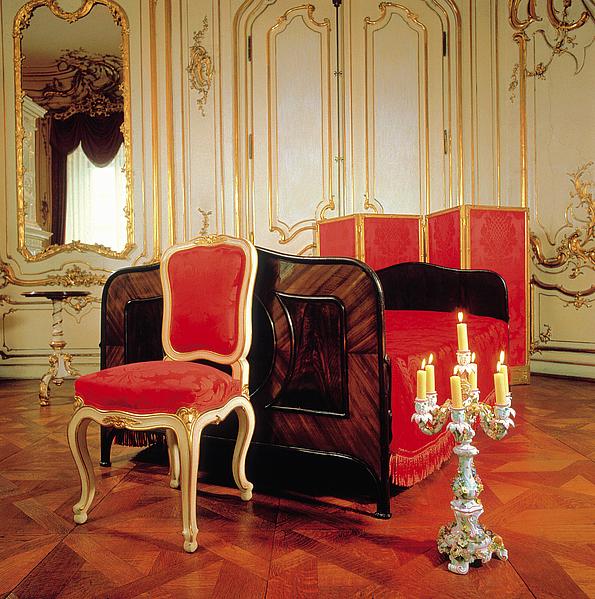 Bild von Kaiserin Sisis Schlafzimmer: Bett und Sessel sind mit rotem Stoff überzogen.