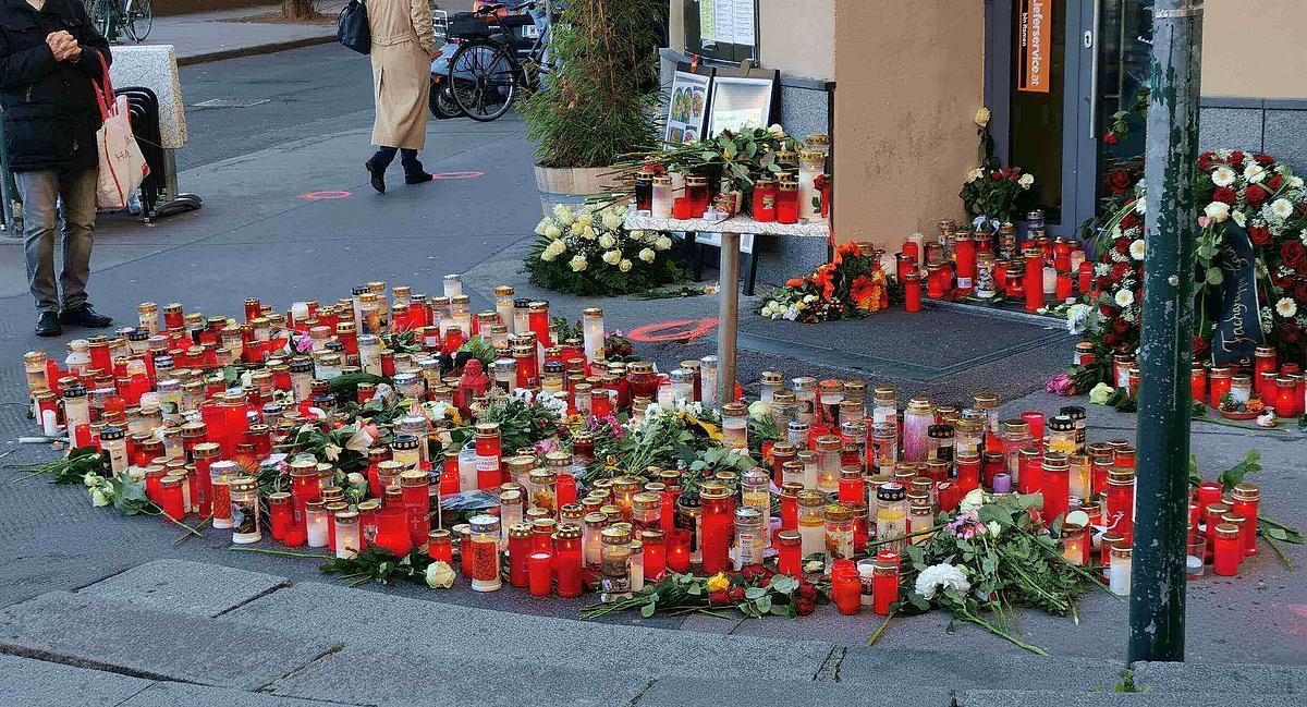 Ein Halbkreis aus Kerzen und Blumen ist vor dem Eingang eines Lokals aufgestellt.