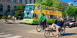 Fahrräder und Sightseeingbus bei einer Ampel in Wien