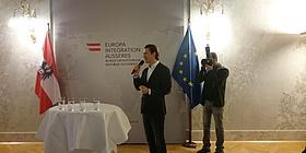 Sebastian Kurz neben Tisch und zwischen Österreich-Flagge und EU-Flagge