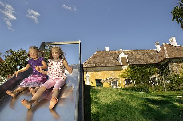 Zwei Kinder auf der Rutsche des Kinderspielplatzes im Meierhof von Schlosshof
