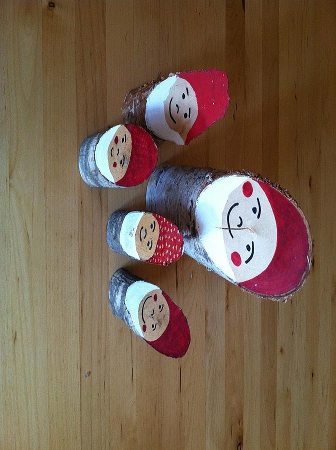Weihnachtsmänner mit roter Mütze aus einem Stück Baumstamm gebastelt