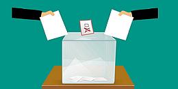 zwei Hände werfen Wahlzettel in Wahlurne
