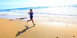 Eine junge, sportliche Frau, die am Strand entlangjoggt 