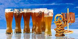 Bier und Brezeln aufgereiht vor blauem Hintergrund