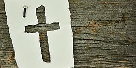 Kreuz in Papier gestanzt mit Nagel an der Wand