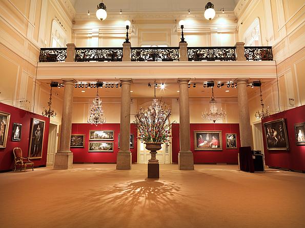 Innenraum des Dorotheum Wien mit Schaustellung von Bildern auf roter Rückwand, Gallerie und Säulen