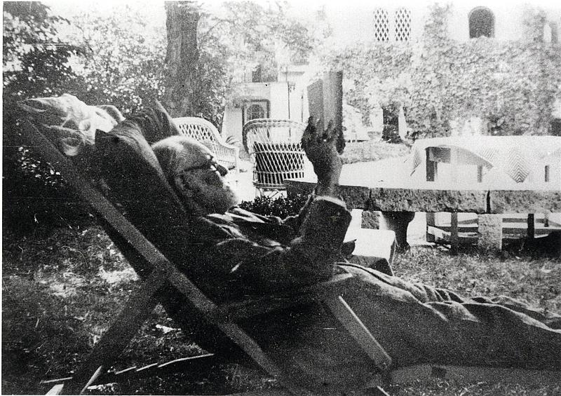 Ein älterer Mann sitzt in einem Liegestuhl und liest ein Buch.