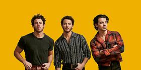 Die Band "Jonas Brothers" vor einem orangen Hintergrund