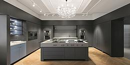 Küche in schlichtem grauen Design mit großem Luster an der Decke