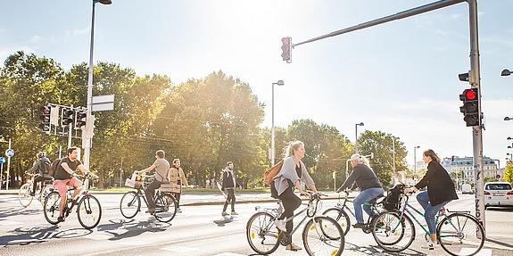 Das Bild zeigt einen Zebrastreifen mit Radfahrern und Fußgängern.