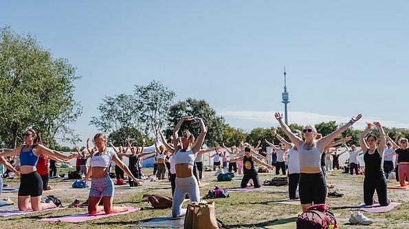 Eine Menschengruppe, die gemeinsam im Freien Yoga macht.