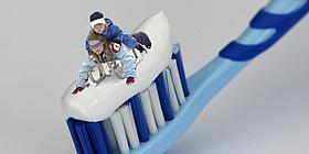 Mutter und Sohn, die auf der schneeweißen Zahnpasta auf einer Zahnbürste Schlitten fahren