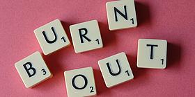 Burnout in Scrabble-Buchstaben vor rosarotem Hintergrund